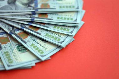 Kırmızı arka planda büyük miktarda yüz dolarlık banknot var. ABD 'de vergilendirme ve para yapma kavramı
