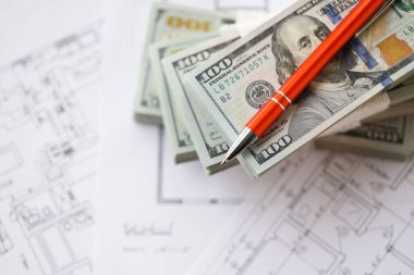 Kalemle birlikte yüklü miktarda Amerikan doları banknotları ve konut projesinin planları yakın plan. Yatırım ve inşaat projesi kavramı