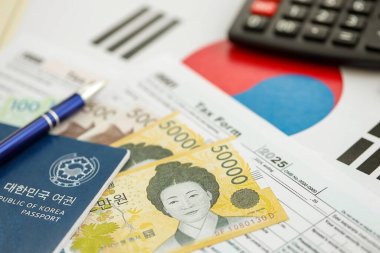 Güney Kore büyük miktarda para kazandı. Masada kalem, hesap makinesi, pasaport ve vergi formları var. Vergi ödeme ve muhasebe kavramı