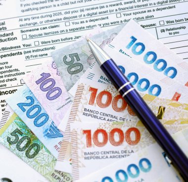 Arjantin pezosu. Büyük miktarda para. Masada, kalem ve vergi formları var.