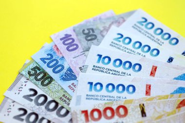 Arjantin pezosu büyük miktarlarda banknotlar sarı renkli masaya yakın duruyor. Finans ve bankacılık kavramı