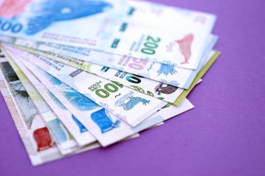 Arjantin pezosu büyük miktarda para mor renkli masaya yakın duruyor. Finans ve bankacılık kavramı