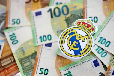 KYIV, UKRAINE - 23 Şubat 2025 Real Madrid CF futbol kulübü rozeti büyük miktarda EURO para banknotlarının üzerinde yatıyor