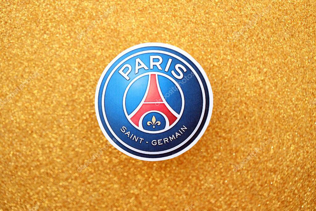 KYIV, UKRAINE - FEBRUARY 23, 2025 Paris Saint Germain FC football club badge lies on golden yellow glitter background banner