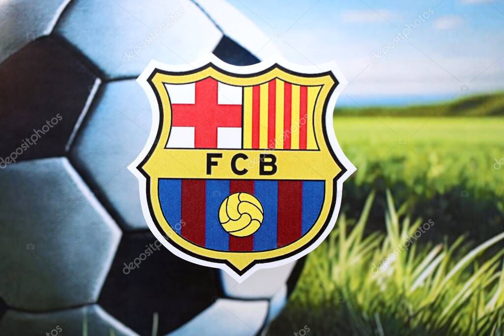 KYIV, UKRAINE - FEBRUARY 23, 2025 FC Barcelona football club badge lies on soccer ball background banner