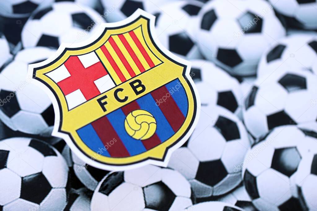 KYIV, UKRAINE - FEBRUARY 23, 2025 FC Barcelona football club badge lies on soccer balls background banner
