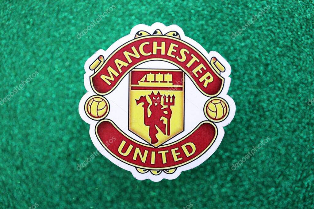 KYIV, UKRAINE - FEBRUARY 23, 2025 Manchester United FC football club badge lies on emerald green glitter background banner