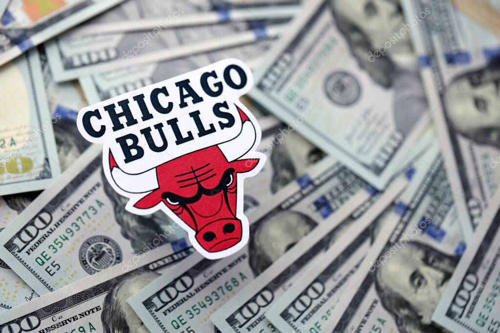 KYIV, UKRAINE - FEBRUARY 23, 2025 Chicago Bulls basketball team badge lies on big amount of hundred US dollar bills close up