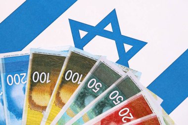 Israel New Shekels banknotları ulusal bayrak üzerinde. İsrail 'in şu anki para faturaları büyük oranda bayrağın üzerinde yatıyor. İsrail 'de iş ve yatırım kavramı
