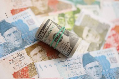 Amerikan dolarlarının rulosu Pakistan 'daki büyük miktardaki banknotların üzerinde yatıyor. Amerikan para demeti Pakistan 'ın para banknotlarında yatıyor. Pakistan 'da ekonomi ve döviz kuru kavramı