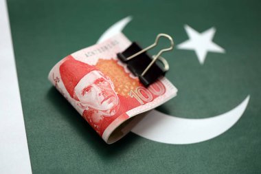 Pakistan bayrağı üzerinde Pakistan banknotları. Pakistan 'ın mevcut para faturaları büyük miktarlarda pankartta yatıyor. Pakistan 'da ekonomi ve ticaret kavramı