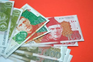 Pakistan kırmızı arka planda banknotlar halinde. Pakistan 'ın mevcut para faturaları büyük miktarda masada yatıyor. Pakistan 'da iş ve yatırım kavramı