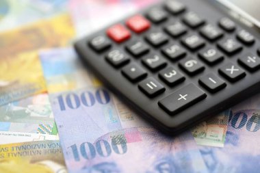 İsviçre frangı banknotları ve hesap makinesi. Mevcut frank para faturaları ve calc büyük miktarda masada yatıyor. İsviçre 'de vergilendirme ve para konsepti