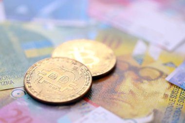 İsviçre frangı banknotları ve bitcoin. Mevcut frank para ve bit para büyük miktarda masada yatıyor. İsviçre 'de vergilendirme ve iş kavramı