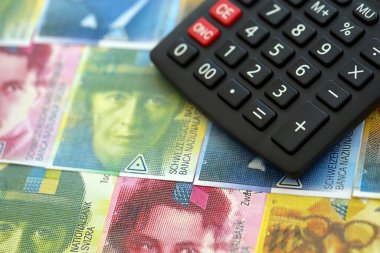 İsviçre frangı banknotları ve hesap makinesi. Faturalar ve kalibreler masanın üzerinde duruyor. İsviçre 'de vergilendirme ve para konsepti