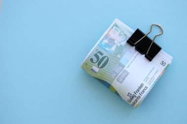 Mavi arka planda İsviçre frangı banknotları. Mevcut frank para faturaları büyük miktarda masada yatıyor. İsviçre 'de iş ve yatırım kavramı