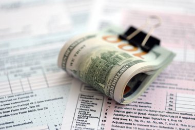 Birleşik Devletler 'in 100 dolarlık banknotları bireysel gelir vergisi iadesi formlarıyla dolu. ABD 'de vergilendirme ve muhasebe kavramı