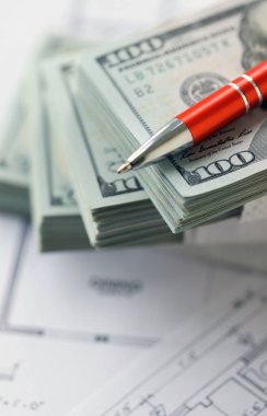 Kalemle birlikte yüklü miktarda Amerikan doları banknotları ve konut projesinin planları yakın plan. Yatırım ve inşaat projesi kavramı