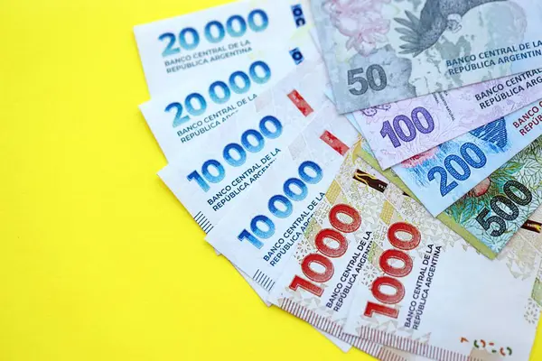 Arjantin pezosu büyük miktarlarda banknotlar sarı renkli masaya yakın duruyor. Finans ve bankacılık kavramı