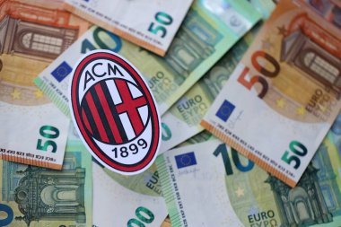 KYIV, UKRAINE - 23 Şubat 2025 AC Milan futbol kulübü rozeti büyük miktarda EURO para banknotları üzerinde yatıyor