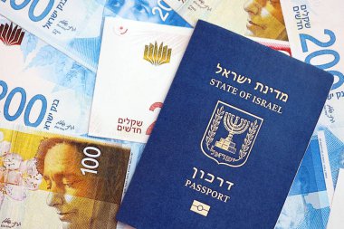 Israel New Shekels banknotları ve pasaportu. İsrail 'in mevcut para faturaları ve biyometrik geçiş kartı büyük miktarda masada yatıyor. İsrail 'de seyahat ve tatil kavramı