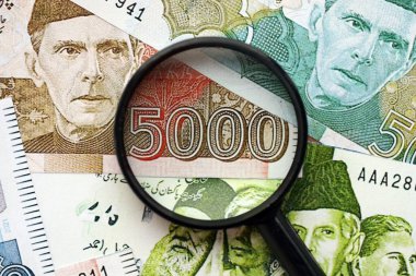 Pakistan banknotları ve büyüteç. Pakistan 'ın mevcut para ve büyüteç faturaları büyük miktarda masanın üzerinde duruyor. Pakistan 'da mali izleme ve vergilendirme kavramı