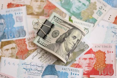 Amerikan dolarlarının rulosu Pakistan 'daki büyük miktardaki banknotların üzerinde yatıyor. Amerikan para demeti Pakistan 'ın para banknotlarında yatıyor. Pakistan 'da ekonomi ve döviz kuru kavramı