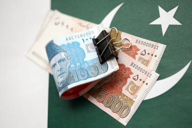 Pakistan bayrağı üzerinde Pakistan banknotları. Pakistan 'ın mevcut para faturaları büyük miktarlarda pankartta yatıyor. Pakistan 'da ekonomi ve ticaret kavramı
