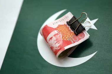Pakistan bayrağı üzerinde Pakistan banknotları. Pakistan 'ın mevcut para faturaları büyük miktarlarda pankartta yatıyor. Pakistan 'da ekonomi ve ticaret kavramı