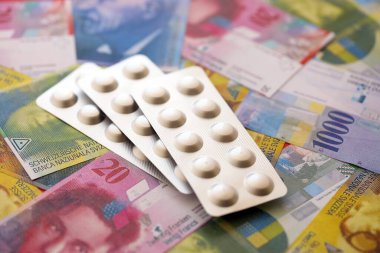 İsviçre frangı ve ilaç hapları. Mevcut para ve uyuşturucu banknotları büyük miktarda masada yatıyor. İsviçre 'de ilaç ve eczane kavramı