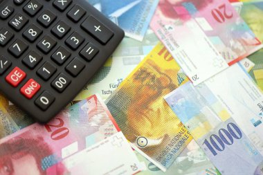 İsviçre frangı banknotları ve hesap makinesi. Mevcut frank para faturaları ve calc büyük miktarda masada yatıyor. İsviçre 'de vergilendirme ve para konsepti