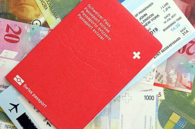 İsviçre frangı banknotları ve biletli pasaport. Mevcut banknotlar ve biyometrik geçiş kartları büyük miktarda masada yatıyor. İsviçre 'de seyahat ve tatil kavramı
