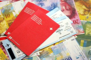 İsviçre frangı banknotları ve biletli pasaport. Mevcut banknotlar ve biyometrik geçiş kartları büyük miktarda masada yatıyor. İsviçre 'de seyahat ve tatil kavramı