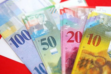 İsviçre frangı banknotları ve bayrağı. Mevcut para banknotları büyük miktarda bayrağın üzerinde yatıyor. İsviçre 'de iş ve yatırım kavramı
