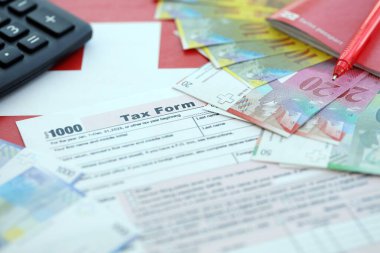 İsviçre frangı banknotları ve vergi formları. Mevcut para faturaları vergi formu ve bayraklarda yatıyor. İsviçre 'de vergilendirme kavramı