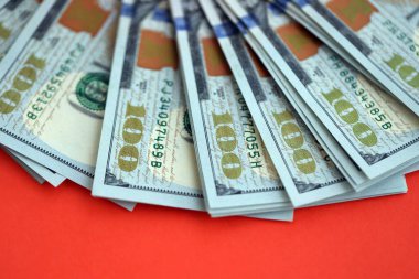 Kırmızı arka planda büyük miktarda yüz dolarlık banknot var. ABD 'de vergilendirme ve para yapma kavramı