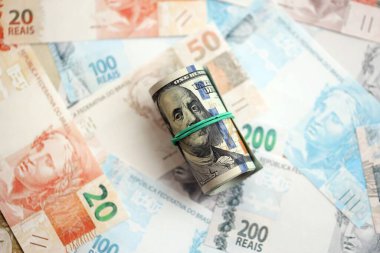 Bir tomar Amerikan doları büyük miktarda Brezilya banknotlarının üzerinde yatıyor. Amerikan parası Brezilya 'nın para akışında yatıyor. Brezilya 'da ekonomi ve döviz kuru kavramı