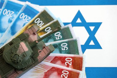 Israel New Shekels 'ın banknotları ve oyuncak tankları bayrağın üzerinde. İsrail 'in şu anki para ve tankı büyük oranda bayraklar üzerinde duruyor. İsrail 'de ordu fonları ve silah satışları kavramı