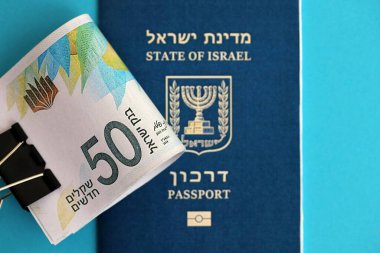 Israel New Shekels banknotları ve mavi arka planda pasaport. İsrail 'in şu anki para banknotları büyük oranda mavi üzerine yatar. İsrail 'de finans ve nakit kavramı