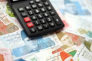 Pakistan banknotları ve hesap makinesi. Pakistan 'ın mevcut para ve hesap makinesi büyük miktarda masada yatıyor. Pakistan 'da vergi ve para sayımı kavramı