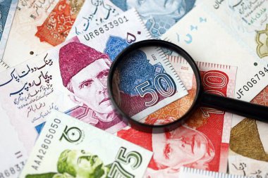 Pakistan banknotları ve büyüteç. Pakistan 'ın mevcut para ve büyüteç faturaları büyük miktarda masanın üzerinde duruyor. Pakistan 'da mali izleme ve vergilendirme kavramı