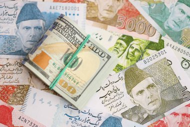 Bir sürü Amerikan doları Pakistan Rupileri 'nin banknotlarına yakın duruyor. Amerikan para demeti Pakistan 'ın para banknotlarında yatıyor. Pakistan 'da ekonomi ve döviz kuru kavramı