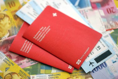 İsviçre frangı banknotları ve biletli pasaport. Mevcut banknotlar ve biyometrik geçiş kartları büyük miktarda masada yatıyor. İsviçre 'de seyahat ve tatil kavramı