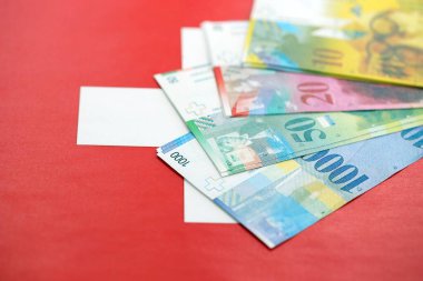 İsviçre frangı banknotları ve bayrağı. Mevcut para banknotları büyük miktarda bayrağın üzerinde yatıyor. İsviçre 'de iş ve yatırım kavramı