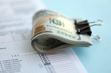 Birleşik Devletler 'in 100 dolarlık banknotları bireysel gelir vergisi iadesi formlarıyla dolu. ABD 'de vergilendirme ve muhasebe kavramı