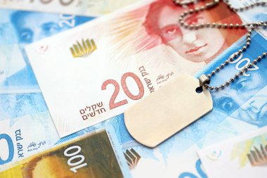 İsrail Yeni Şekelleri 'nin banknotları ve askeri simgesi. İsrail 'in mevcut para faturaları ve künyeleri büyük miktarda masada yatıyor. İsrail 'de askerlik kavramı