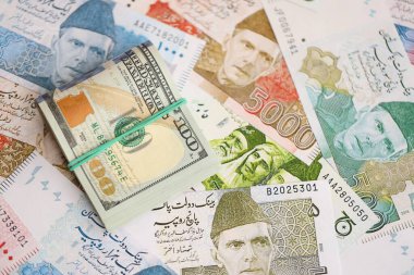 Amerikan dolarları yığını Pakistan Rupi banknotlarının büyük bir miktarına yakın duruyor. Amerikan para demeti Pakistan 'ın para banknotlarında yatıyor. Pakistan 'da ekonomi ve döviz kuru kavramı