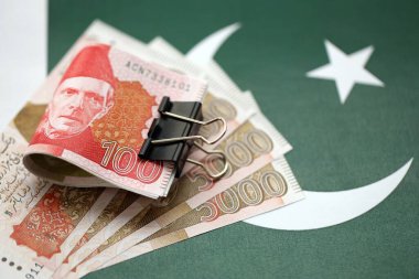Pakistan bayrağı üzerinde Pakistan banknotları. Pakistan 'ın mevcut para faturaları büyük miktarlarda pankartta yatıyor. Pakistan 'da ekonomi ve ticaret kavramı