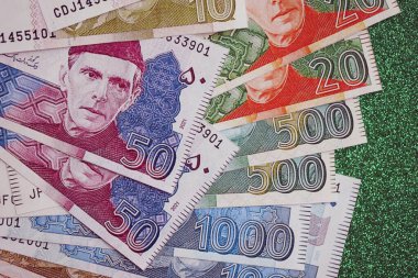 Pakistan parlayan yeşil arka planda banknotlar halinde. Pakistan 'ın mevcut para faturaları büyük miktarda masada yatıyor. Pakistan 'da iş ve yatırım kavramı
