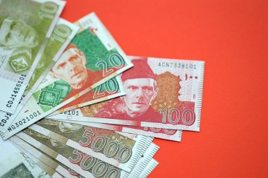Pakistan kırmızı arka planda banknotlar halinde. Pakistan 'ın mevcut para faturaları büyük miktarda masada yatıyor. Pakistan 'da iş ve yatırım kavramı
